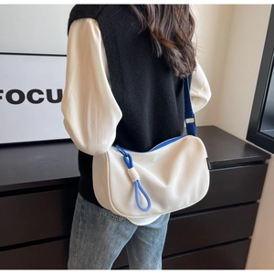 Detailed shot of crescent moon bag with blue zipper contrast and adjustable strap