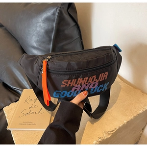 Detailopname van een zwarte nylon crossbodytas met pixeltekst en oranje ritstrekker