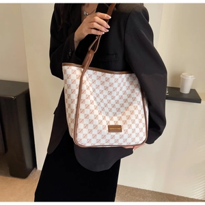 Detail of checkered tote bag with brown leather handles and fashion logo patch