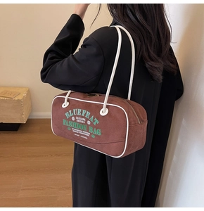 Détail du sac cylindrique marron givré avec coutures blanches contrastées et bandoulière