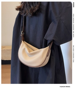 Détail du sac demi-lune crème avec bordure en cuir marron et texture grainée