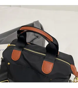 Detail of durable nylon tote bag with leather拼接, gold zipper, and reinforced handles