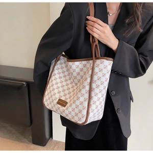 Detail of white and red checkered tote bag with brown leather strap and brand label