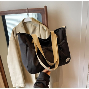 Detailaufnahme der großen schwarzen Canvas-Tasche mit beigen Griffen und Seitentaschen