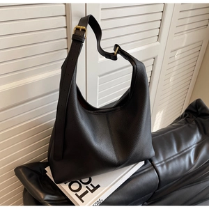 Detail of black lychee grain leather hobo bag with wide strap and golden buckle