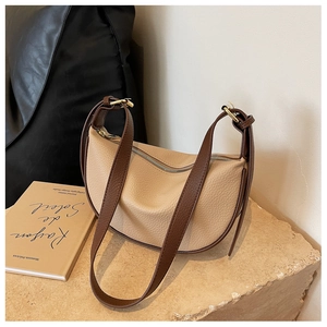 Détail du sac demi-lune beige en cuir grainé avec bandoulière réglable marron sur pierre
