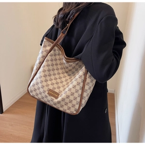 Detail of vintage monogram pattern tote bag with leather trim and fashion brand tag