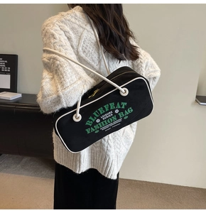 Vue détaillée d'un sac d'épaule en toile noire avec passepoil blanc et texte vert vif