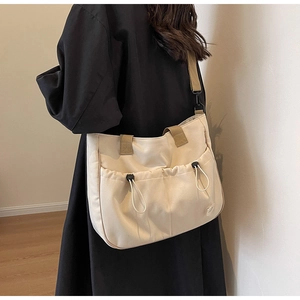 Detail der cremeweißen Canvas-Einkaufstasche mit Kordelzugtaschen und breitem Schultergurt
