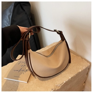 Gros plan d'un sac bandoulière en cuir beige grainé avec bandoulière marron réglable