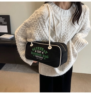 Détail du sac polochon en toile noire avec passepoil blanc et logo de style sportif