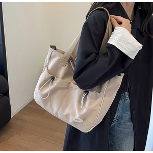 Detailansicht der Canvas-Einkaufstasche mit funktionalen Kordelzugtaschen und Stickerei