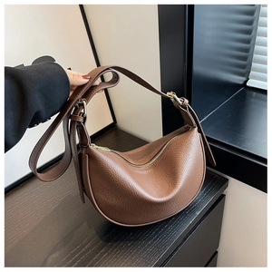 Détail de la texture cuir marron grainé et de la fermeture éclair dorée du sac