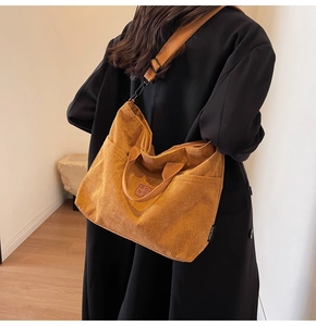 Detailed texture of brown corduroy tote bag showing side pockets and adjustable strap