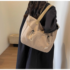 Detail der beigen Canvas-Tragetasche mit Kordelzugtasche und Good Luck-Etikett für Damen
