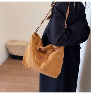 Brown corduroy tote bag detail showing leather patch, side pocket, and adjustable strap