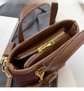 Détail de la fermeture éclair dorée fluide sur un sac seau en laine à carreaux