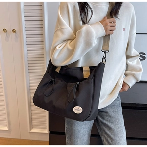 Detailaufnahme der schwarzen Canvas-Tasche mit Kontrastgurt und Good Luck-Patch