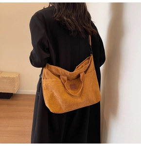 Detail of mustard yellow corduroy tote bag showing leather logo and texture