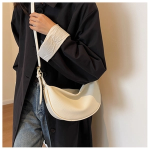 Détail d'un sac hobo croissant beige en cuir à motif litchi porté à l'épaule