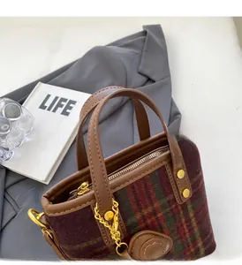 Gros plan du sac vintage en laine écossaise rouge et verte avec anses en cuir