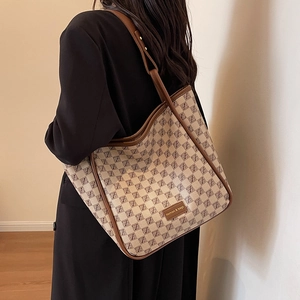 Large capacity monogram tote bag with brown leather trim shown on a female model