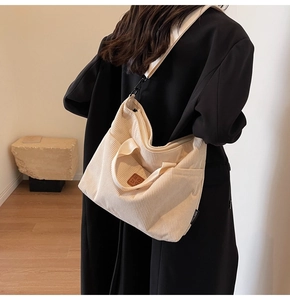 Detail view of beige corduroy tote bag showing side pocket and strap with metal buckle
