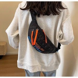 Detailopname van een zwarte nylon crossbody tas met feloranje ritsen en grafische details