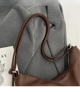 Close-up of smooth long shoulder strap and silver hardware on dark brown leather bag