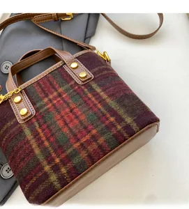 Gros plan du sac seau à carreaux marron avec garniture en cuir et clous dorés