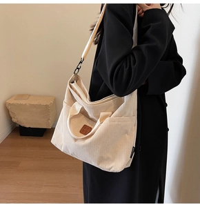 Detail of off-white corduroy tote bag showing textured fabric and brown leather logo patch