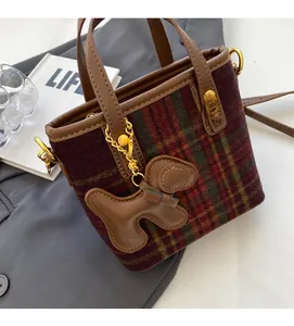 Détail d'un sac à main rétro à carreaux avec garniture en cuir et breloque chiot