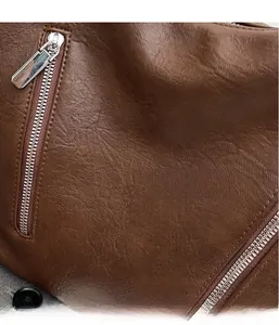 Detailed macro view of brown pebbled leather texture and silver metal zipper on a bag