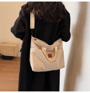 Detail of off-white corduroy tote bag showing textured fabric and side pockets