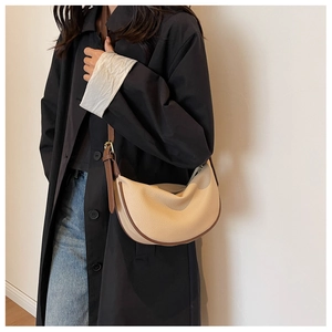 Gros plan du sac hobo en cuir crème avec bandoulière marron et grain galet