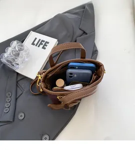 Intérieur spacieux du sac seau marron foncé montrant sa capacité pour deux mobiles