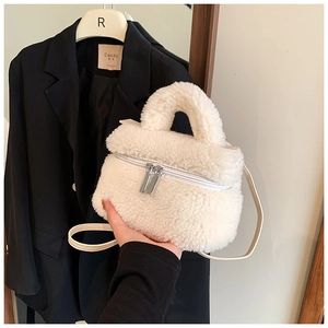Detailansicht einer weißen Plüschhandtasche mit Metallreißverschlüssen und Schultergurt