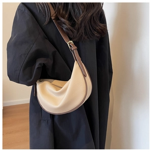 Détail de la bandoulière réglable en cuir marron sur le sac demi-lune beige contrasté