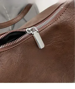 Close-up of sleek silver hardware zipper on brown lychee grain PU leather bag