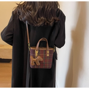 Détail d'un sac seau vintage à carreaux avec un adorable pendentif en cuir en forme de chien