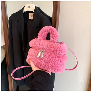 Detail van roze pluchen handtas met leren schouderriem en dubbele metalen ritssluitingen