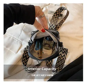 Vue intérieure d'un sac bandoulière en cuir noir avec large bandoulière à motifs