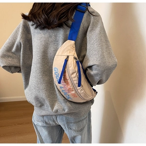 Detail van beige crossbody borsttas met blauwe riem en Good Luck print ontwerp