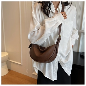 Détail d'un sac bandoulière en cuir grainé marron foncé avec bandoulière réglable