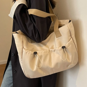 Große beige Canvas-Tragetasche mit Kordelzugtaschen am Model in minimalistischer Umgebung