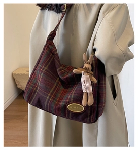 Detail of red plaid woolen hobo bag with gold logo plaque and plush bunny keychain