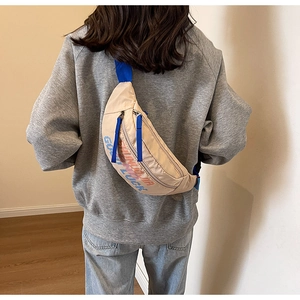 Detailweergave van grote beige crossbodytas met blauwe banden getoond op een model