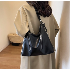 Detail view of black large capacity tote bag with silver zippers and chain strap detail