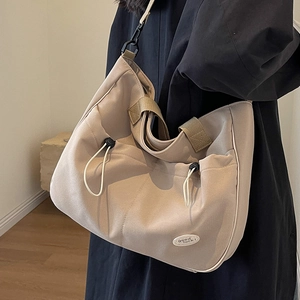 Minimalistische beige Canvas-Tragetasche mit Kordelzug und Good Luck-Tag am Model gezeigt