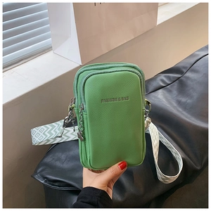 Détail du sac à téléphone vert texturé avec double zip et bandoulière tissée large